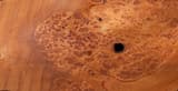 Sheet of reddish burl veneer, clusters of small dark eyes with the grain swirling around each one