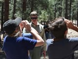 Children at a forestry camp measuring a pine tree's height with a clinometer